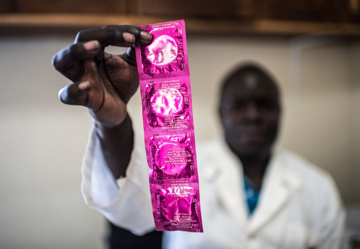 A health practitioner holds up condoms in Gulu clinic, Uganda