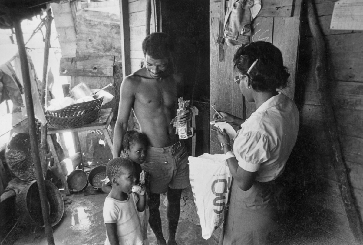 Community outreach worker visiting a father and his children. Haiti, 1983.