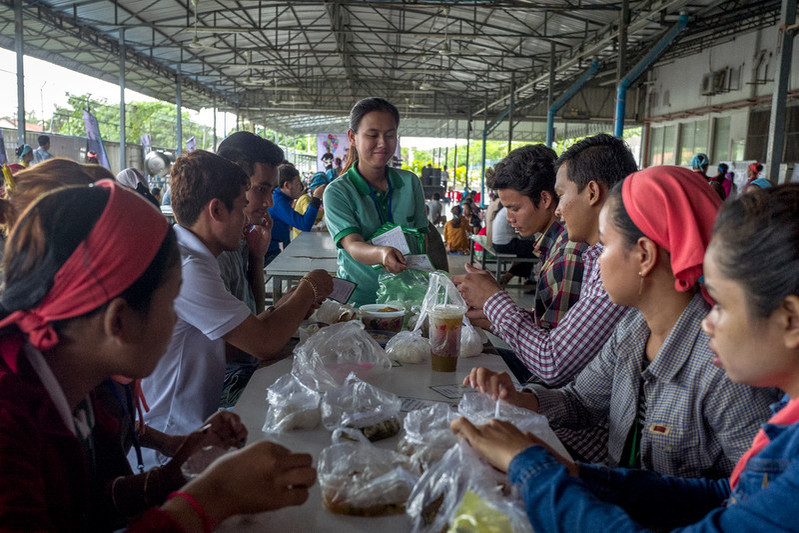 25-year-old RHAC midwife, Chandy, gives information leaflets to a group of garment workers on their lunch break during a health event held in the Propitious garment factory. Many of the women would have left school at an early age and little or no knowledge of reproductive health.  