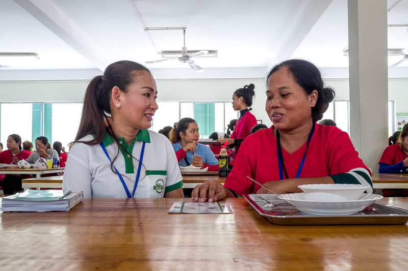 RHAC hotline counsellor, Ing Samnang, speaks to a garment worker during her lunch break inside the canteen of the Dewhirst Garment Factory. 