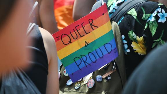 Rainbow flag which reads "queer & proud"