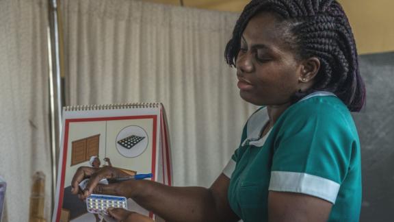 A healthcare worker in Ghana shows a client the Pill